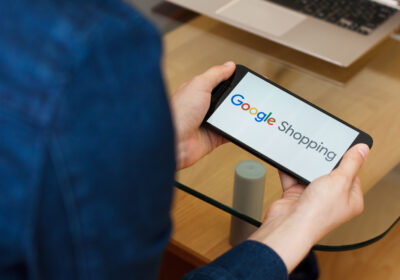 kvinna med telefon, text Google shopping på skärmen