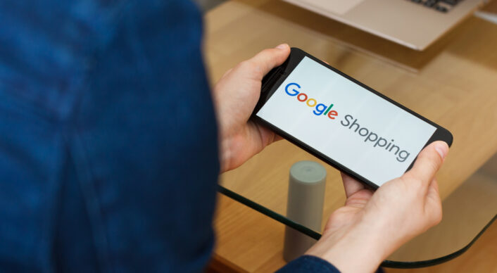 kvinna med telefon, text Google shopping på skärmen